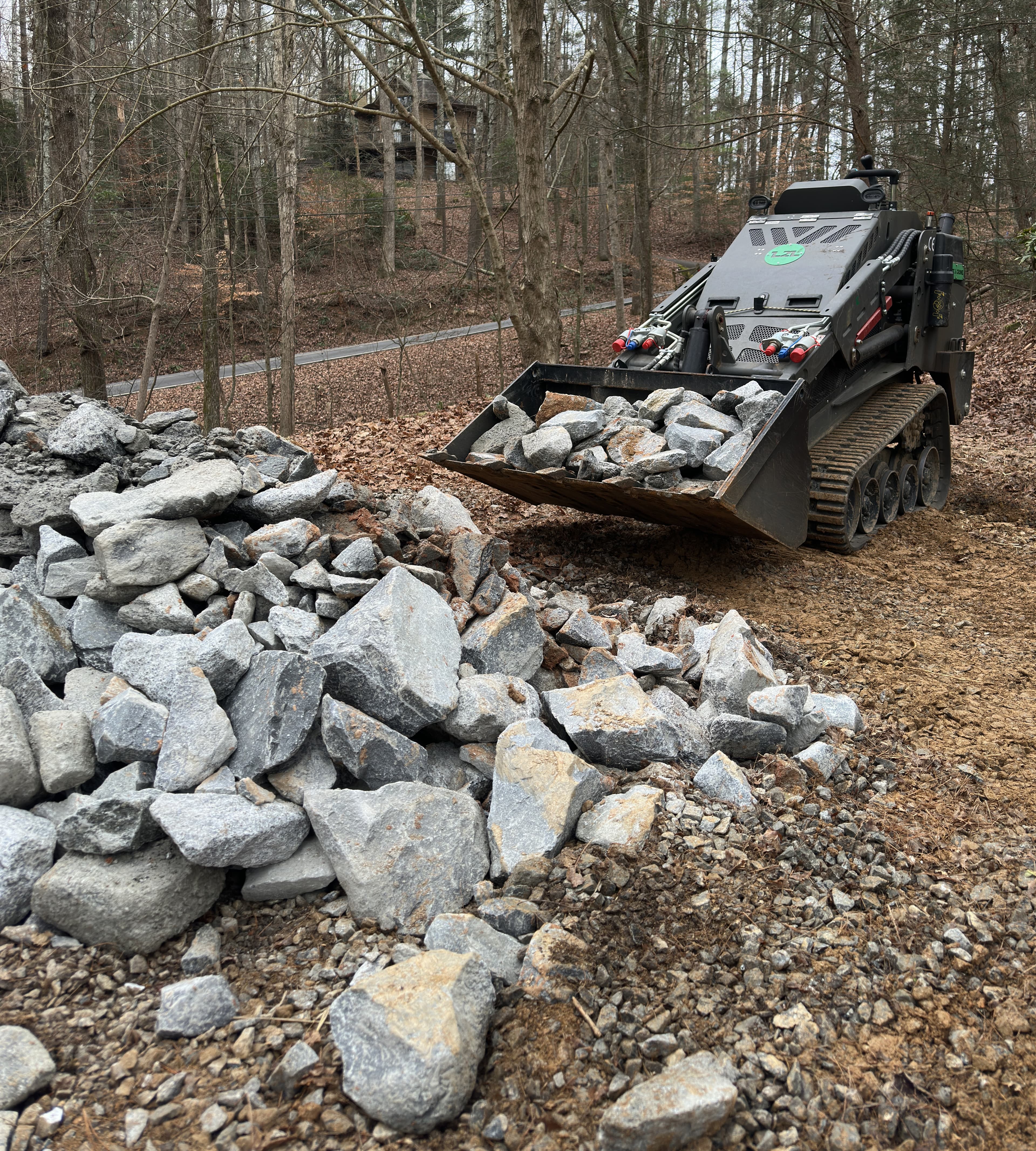 Skid steer moving rock for property work in North Georgia